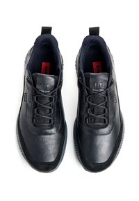 Baskets de sport noires avec un dessus en cuir lisse, une languette en tissu texturé, des lacets ronds et une semelle rembourrée. Marquage discret sur la languette.