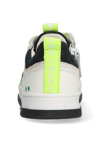 Hvide sneakers med sorte accenter, tekstureret ruskind og en klar grøn hæltab. Har et logo og en kontrastfyldt gummisål.