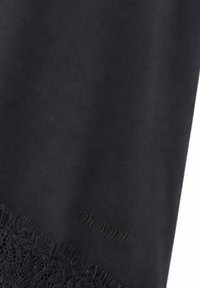 Tissu noir avec une bordure en dentelle délicate et un texte embossé subtil « Oh April » près du bord inférieur.