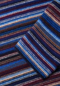 Tissu tissé présentant de larges rayures en bleu, marron, bordeaux et crème. La texture est douce avec un motif de tricot dense et chaud.