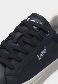 Μαύρο δερμάτινο αθλητικό παπούτσι με μαύρα κορδόνια, λευκό λογότυπο "Lee" στο πλάι και λευκή λαστιχένια σόλα, κλειστή γωνιακή άποψη.