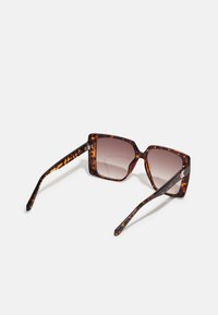Ochelari de soare tortoishell maro cu ramă pătrată, lentile cu gradient și brațe subțiri cu un design subtil. Accentați cu accesorii de marcă.