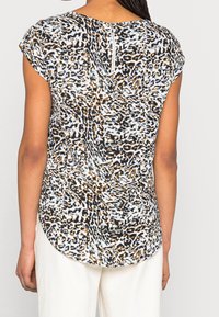 Blusa de manga corta con estampado de leopardo en tonos azules, marrones y negros. Tejido suave y ligero con dobladillo redondeado y detalle de cremallera en la espalda.