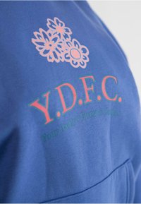 Blå bomulds sweatshirt med pink blomster grafik og teksten "Y.D.F.C." og "Your Daddy's Favorite Clothes." Glat tekstur, afslappet design.
