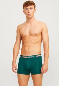 Heren groene boxershorts met een contrasterende zwart en oranje tailleband, met een strakke pasvorm en een gladde stofstructuur.