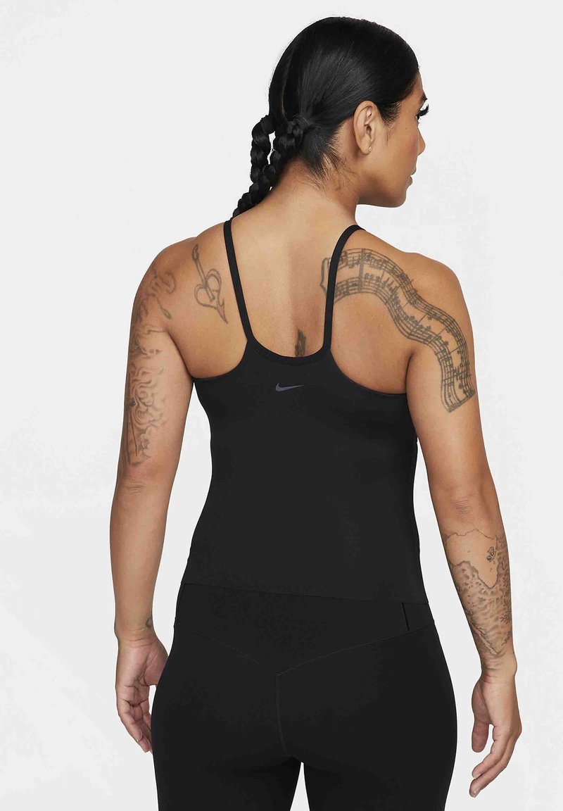Canotta sportiva nera con spalline sottili e design aderente. Presenta un piccolo logo Nike sul retro e tatuaggi intricati sulle braccia.