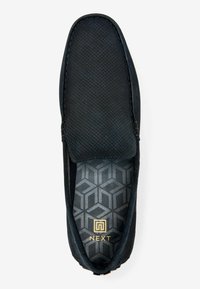 Sort loafer med en textureret overdel, glat trim og en indersål med geometrisk mønster og et guld logo. Rundt tå, slip-on design.