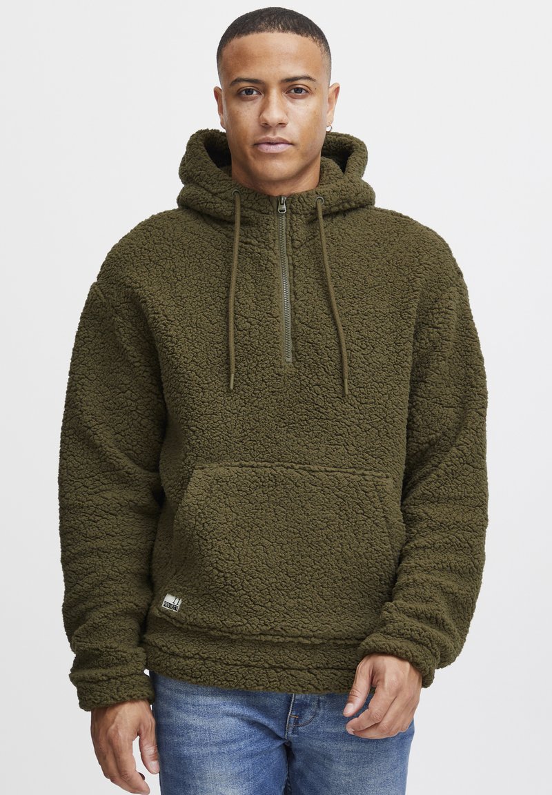 Olive green fleece hoodie with a zippered neck, kangaroo pocket, and textured surface. Features drawstrings and logo tag at the hem.