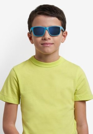 Lunettes de soleil bleues avec des verres foncés, portées par un enfant en t-shirt jaune vif. L'arrière-plan est blanc uni.