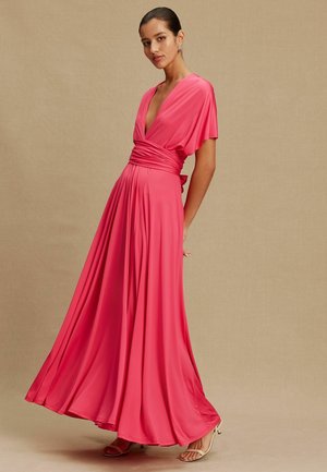 Lång rosa omlottklänning med djup V-ringning, korta ärmar och flytande kjol. Tillverkad av mjukt tyg, har detaljer med knuten midja och mjuk drapering.