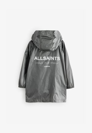 Pelēkā kapuci lietusmētelis ar elastīgām aprocēm, aizmugurē ar baltu drukātu tekstu "ALLSAINTS" un logotipiem vairākās valodās. Viegls materiāls.