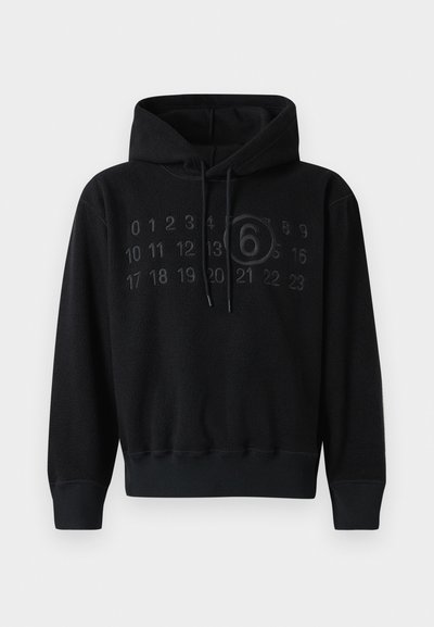 Melnas vilnas kapuci, kas raksturīga ar priekšpusi, uz kuras attēloti skaitļi un aplis ar skaitli 6. Iekļauta kapuce ar saites un ribota aproce un apakša.