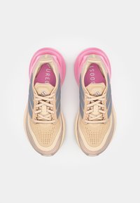 Beige running shoes with pink rubber sole, grey stripes, and a mesh upper. Features a cushioned insole with "PUREBOOST" printed in pink.