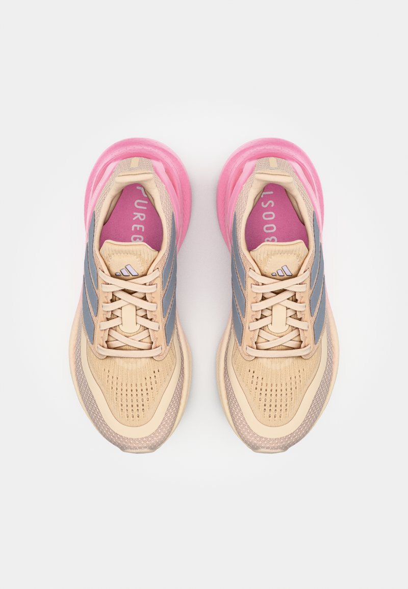 Baskets de course beiges avec semelle en caoutchouc rose, rayures grises et tige en mesh. Comprend une semelle intérieure rembourrée avec "PUREBOOST" imprimé en rose.