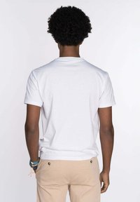 Camiseta de algodón blanca con escote redondo y mangas cortas. La tela parece suave, sin patrones o gráficos visibles.