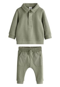 Gaiši zaļš divdaļīgs komplekts, kurā ietilpst teksturēta polo krekls ar garām piedurknēm, apkakli un pogu, kā arī elastīga vidukļa bikses ar kabatām.