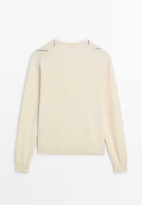 Pull en tricot couleur crème avec manches longues, encolure ronde et accents de coutures discrètes sur les épaules et les manches. Texture douce.