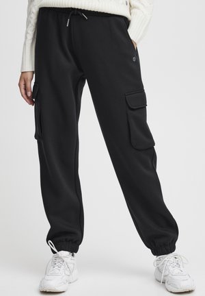 Zwarte cargobroek van sweatstof met een elastische tailleband en koord, afgewerkte enkels en zijzakken met kleppen. Gemaakt van zachte stof.