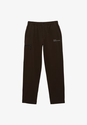 Braune Hose mit elastischem Bund und seitlicher Reißverschluss-Tasche sowie bedrucktem Branding. Hergestellt aus weichem Stoff mit geradem Bein design.