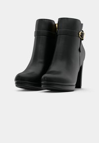 Μαύρες ψεύτικες δερμάτινες μπότες μέχρι τον αστράγαλο με στρογγυλή μύτη, ψηλό τακούνι, πλευρικό φερμουάρ και διακοσμητική λουρί με χρυσή επένδυση.