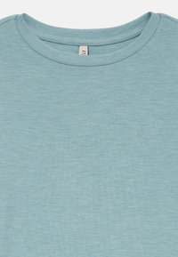 Ljusblått t-shirt med rund halsringning och ribbat krage, med finstickad struktur, som visar övre bröstet och halsringningsområdet.