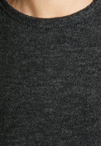 Maglione grigio scuro realizzato in un tessuto morbido e testurizzato. Presenta un collo rotondo e cuciture minimali visibili.