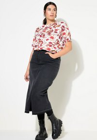 Witte blouse met bloemenpatroon en een losse pasvorm, gecombineerd met een hoge taille, zwarte denim maxi rok en stevige zwarte laarzen.