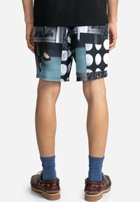 Shorts multicolores présentant un collage de motifs comprenant des pois, des formes géométriques et des impressions photographiques ; fabriqués dans un tissu léger.