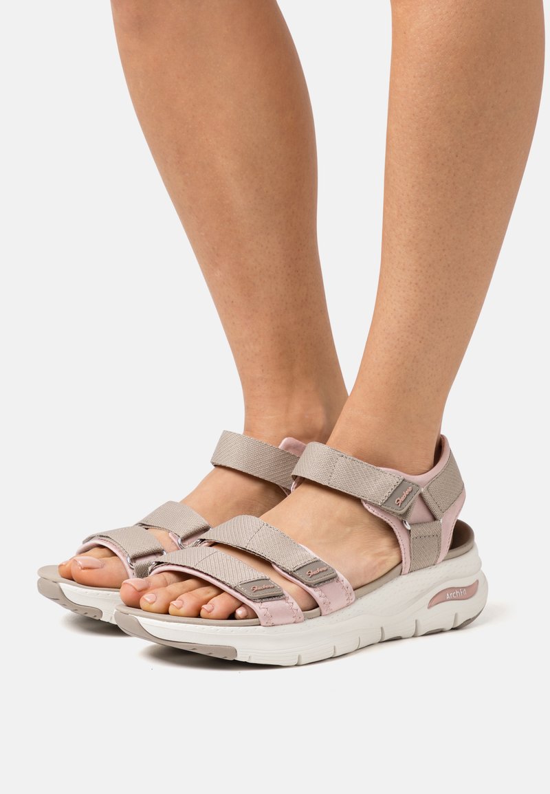 Sandalias de tiras ajustables en beige y rosa con tela texturizada, suela acolchada y una prominente suela blanca. Incluye soporte para el arco.