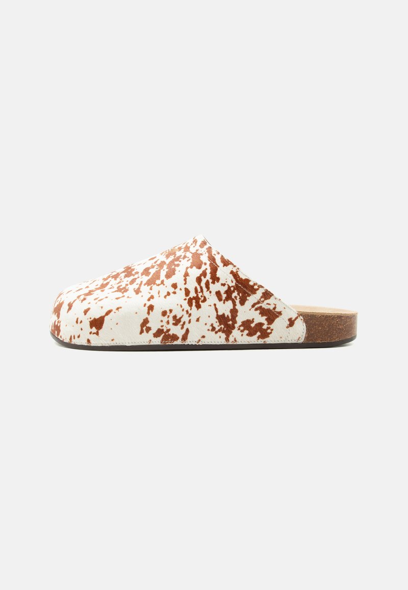 Παπούτσι mule slip-on με λευκό και καφέ πουδρωτό μοτίβο και επίπεδη φελλό σόλα σε μονόχρωμο φόντο.