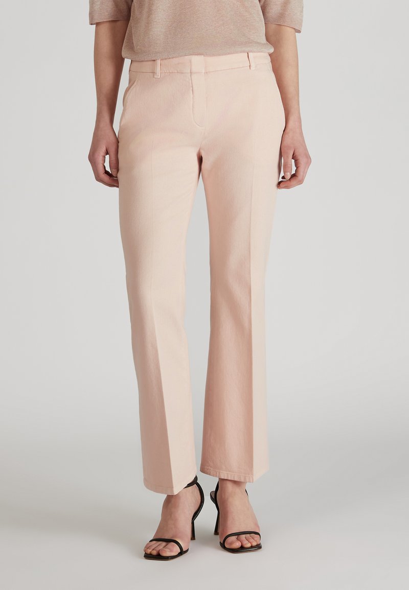 Pantalons ajustés rose clair avec une coupe droite, fabriqués en tissu tissé, dotés de poches latérales et de passants de ceinture, associés à des talons aiguilles noirs à lanières.