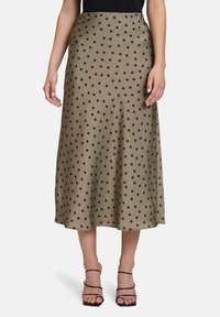 Jupe midi en satin vert olive avec des pois noirs. Présente une silhouette fluide et une texture lisse, avec une taille ajustée.