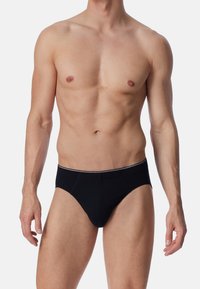 Zwarte herenbriefs gemaakt van zachte stof, met een witte elastische tailleband en een klassiek ontwerp. Strak-fitting, zonder extra patronen.