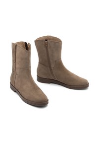 Botas de tobillo de ante marrón con una textura suave, cremallera lateral y puntera redondeada. Suela plana y diseño minimalista.