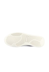 Semelle de chaussure blanche avec des motifs de bande de roulement circulaires et ondulés, des zones de grip texturées, et un panneau logo rectangulaire au centre.
