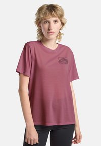 T-shirt à manches courtes bordeaux en tissu léger. Affiche un petit graphique de montagne noir sur la zone de la poitrine gauche.