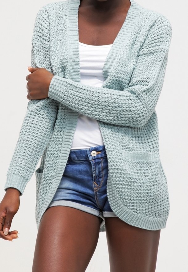 Cárdigan de punto azul claro con un patrón texturizado, apertura frontal y dos bolsillos delanteros. Mangas largas y puños acanalados.