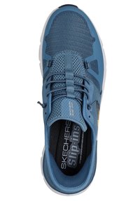 Zapatilla azul con parte superior de malla y cordones elásticos. Presenta una plantilla acolchada etiquetada como "Skechers Goga Max" y una suela blanca texturizada.
