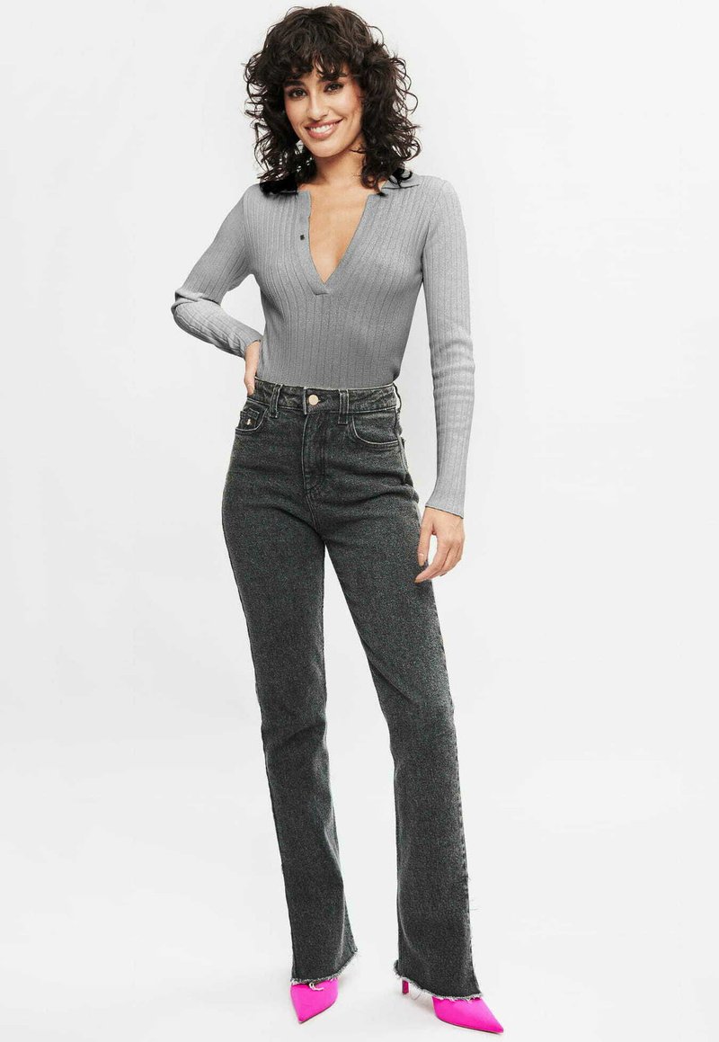 Grijze geribbelde longsleeve bodysuit met een diepe V-hals, gecombineerd met hoge, donkere grijze flared jeans en felroze pumps met puntige neuzen.