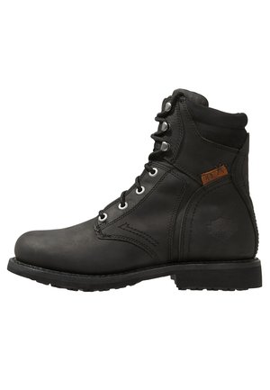 Schwarzer Lederknöchelstiefel mit Schnürvorderseite, Metallösen, gepolstertem Kragen, robuster Sohle und kleinem braunem Etikett an der Seite.