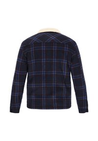 Skjortejakke i ternet flannel i marineblå, rød og blå. Har en krave i cremefarve, lange ærmer og en lige kant bagtil. Blød tekstur.