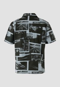Korte mouwen shirt met een collage van zwart-witte fotografische afdrukken op een lichte achtergrond, met een relaxte pasvorm en een naar beneden vallende kraag.
