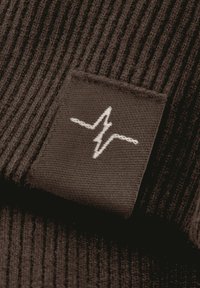 Dunkelbrauner Stoff mit gerippter Textur; hat ein schwarzes Etikett mit einem weißen Herzschlag-Design.