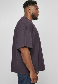 Tricou din bumbac lila, cu croială lejeră, mânecă scurtă, decolteu rotund și textură netedă. Purtați-l cu blugi din denim albastru.