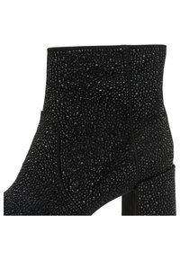 Zwarte enkelboot van gestructureerd materiaal, versierd met glanzende studs, met een blokhak en gladde randen.