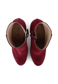 Bottines en daim bordeaux avec un intérieur lisse, fermeture éclair sur le côté et une silhouette incurvée. Nom de la marque "EVITA" visible à l'intérieur.