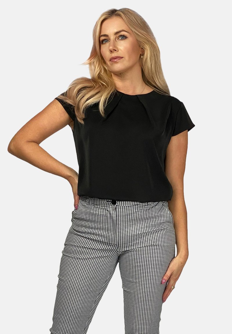 Czarna bluzka z krótkim rękawem, okrągłym dekoltem i subtelnym detalem fałdy, zestawiona z czarno-białymi spodniami w kratę z wysokim stanem.