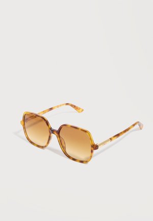 Ochelari de soare pătrați, cu ramă în model scoică de țestoasă și lentile maro cu gradient, cu brațe subțiri, înclinați ușor spre dreapta pe un fundal alb.