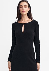 Czarna, prążkowana sukienka z długim rękawem, okrągłym dekoltem i wycięciem w kształcie łezki z przodu, o dopasowanej sylwetce i gładkiej teksturze.