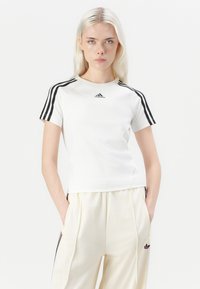 Weißes kurzärmeliges Sportshirt mit schwarzem Drei-Streifen-Design an den Schultern und kleinem Logo in der Mitte. Weicher, glatter Stoff.